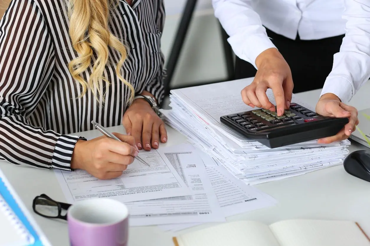 A woman is working on some papers with an accountant.